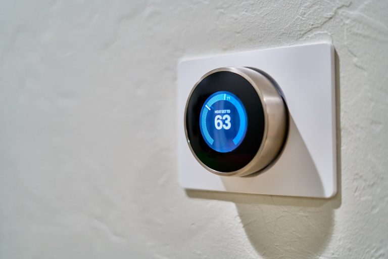 Smart thermostat Nest on wall showing temperature 63